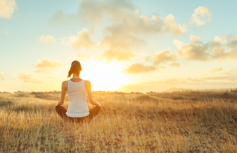 a woman practicing mindfulness meditation in a field