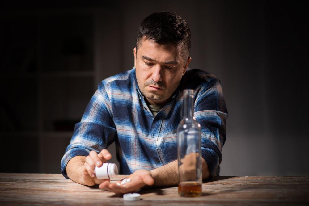man taking pills with alcohol